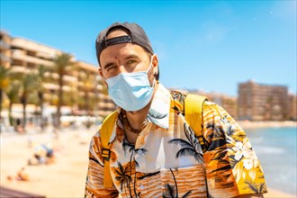 A young man with a tourist surgical mask on the Cura beach in the coastal city of Torrevieja