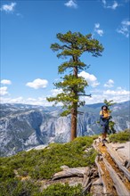 A young man with a brown jacket in Sentinel Dome looking at Upper Yosemite Fall