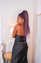 Fashion lifestyle of a black ethnic girl with pink braids and a black dress. Portrait of the girl