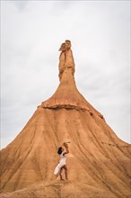 Young brunette Caucasian girl with a white dress and a straw hat in the Castildetierra of the Bardenas Reales desert