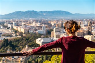 A young tourist looking at the views of the city and the Cathedral of the Incarnation of Malaga from the Gibralfaro Castle in the city of Malaga