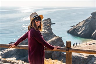 Portrait of a young tourist girl with a hat looking at the beautiful Cala Penon cut off a virgin and hidden beach in Almeria. Mediterranean sea on the coast. Almanzora Caves