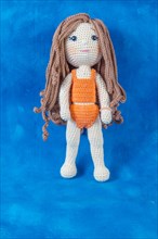 Close-up of a handmade amigurumi doll on a blue background