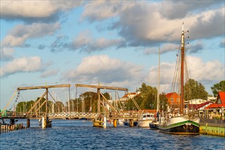 Historic Wieck wooden bascule bridge over the river Ryck and sailing ships in the harbour