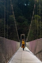 A hiker with a yellow backpack crossing the Holtzarte suspension bridge