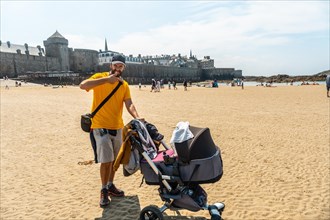 A young father enjoying the summer on the Grande Plage du Sillon de Saint-Malo in French Brittany