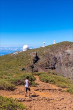 A young woman walking next to the telescopes of the Roque de los Muchachos National Park on top of the Caldera de Taburiente