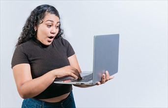 Amazed latin woman using laptop isolated. Surprised girl looking at an promotion on laptop screen
