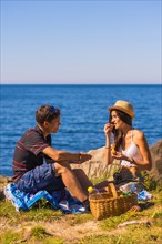 A couple eating potatoes at the picnic in the mountains by the sea enjoying the heat