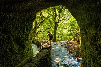 A young woman trekking in the cave at Levada do Caldeirao Verde