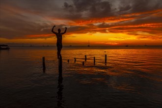 A young man in the water at the Orange Sunset on the West End beach of Roatan. Honduras