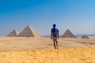 A young man in a blue turban walking next to the Pyramids of Giza