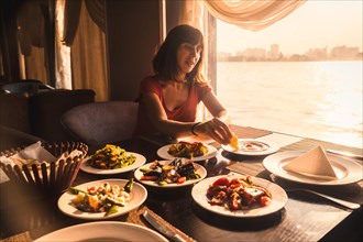 A young tourist having dinner on a boat on the nile a traditional Egyptian meal with the sunset light in the window. Africa