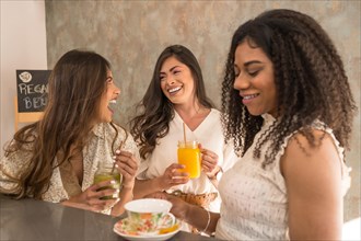 Funny moments of three women laughing and enjoying in a healthy cafeteria