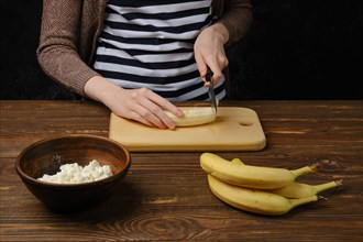 Closeup of female hands cutting banana on a cutting board