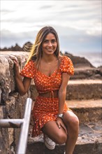 A young brunette Caucasian woman in a red dress on the beach of Itzurrun in the town of Zumaia