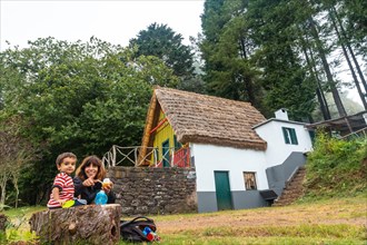 A family in the traditional Madeiran house like those of Santana in the forest of Caldeirao Verde