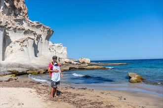 A young father walking with his son along the Enmedio beach in Cabo de Gata on a beautiful summer day