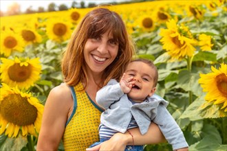 Portrait of a Caucasian mother and her baby laughing in a sunflower setting