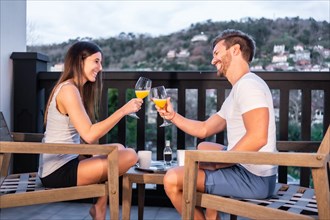 A Caucasian couple having breakfast on the hotel terrace in pajamas. Toasting with orange juice in the morning