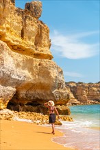 A woman with a hat on vacation in the Algarve on the beach at Praia da Coelha