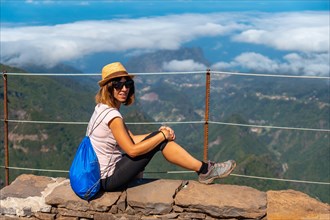 A young female tourist sitting at the Miradouro do Juncal on Pico do Arieiro