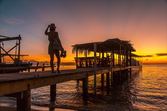 A young girl in a sunset on a pier on a beach on Roatan Island. Honduras