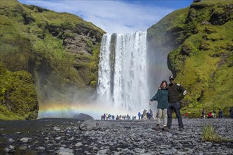 A couple in the famous waterfall visited by hundreds of daily tourists