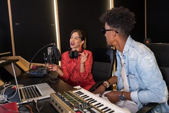Female singer composing and recording new album in studio next to an african pianist