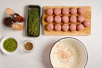 Top view of raw uncooked meatballs on wooden cutting board