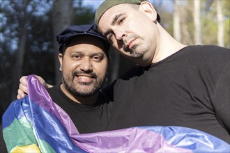 Gay couple in a park holding lgbt rainbow flag
