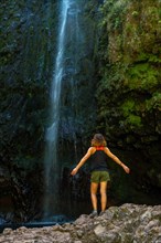 A young woman at the impressive waterfall at the Levada do Caldeirao Verde