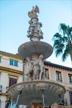 Water fountain in the Plaza de la Constitucion of the city of Malaga and its beautiful palm trees