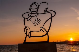 Sculpture in favor of the victims of covid in the orange sunset at Playa del Cura in the coastal city of Torrevieja