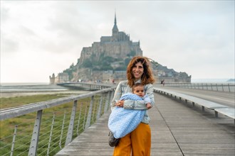 A young mother with her baby visiting the famous Mont Saint-Michel in the Manche department