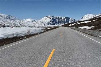 Road by an icy lake in the snowy mountains of Stryn