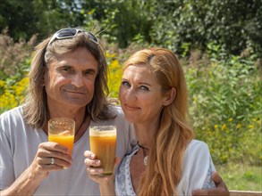 Man and woman in the garden with freshly squeezed fruit juice