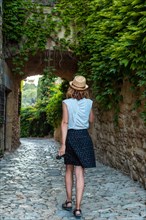 A young tourist walking through the streets of Peratallada medieval town