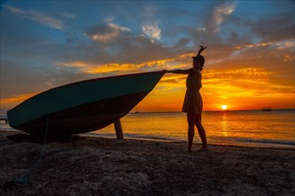 A young woman on the beach in a boat at Roatan Sunset from West End. Honduras
