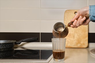 Closeup view of pouring ground coffee into a glass from turk