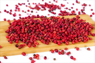 Pink peppercorns on a wooden board isolated on white background and copy space