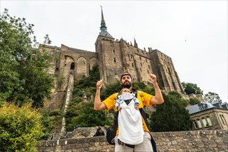 A young father visiting the famous Mont Saint-Michel Abbey in the Manche department