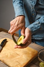 Close up of female hands taking avocado pulp out with spoon