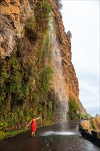 A young woman looking at the waterfall that falls on the road called Anjos Waterfall