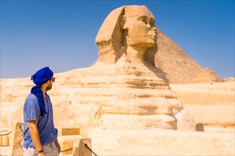 A young tourist near the Great Sphinx of Giza dressed in blue and a blue turban