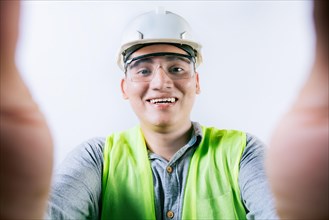 Smiling male engineer taking a selfie looking at camera. Cheerful builder engineer taking a selfie isolated