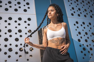 Young woman of black ethnicity with long braids and with tattoos