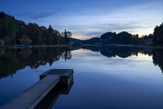 The Hengelesweiher pond in the Hengelesweiher nature reserve in the evening after sunset at blue hour. The lake is calm