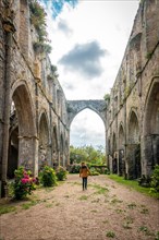 A young woman visiting the ruins of the Abbaye de Beauport church in the village of Paimpol