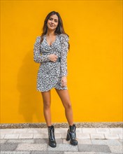 A Caucasian brunette dressed in a beautiful short dress. Yellow background back